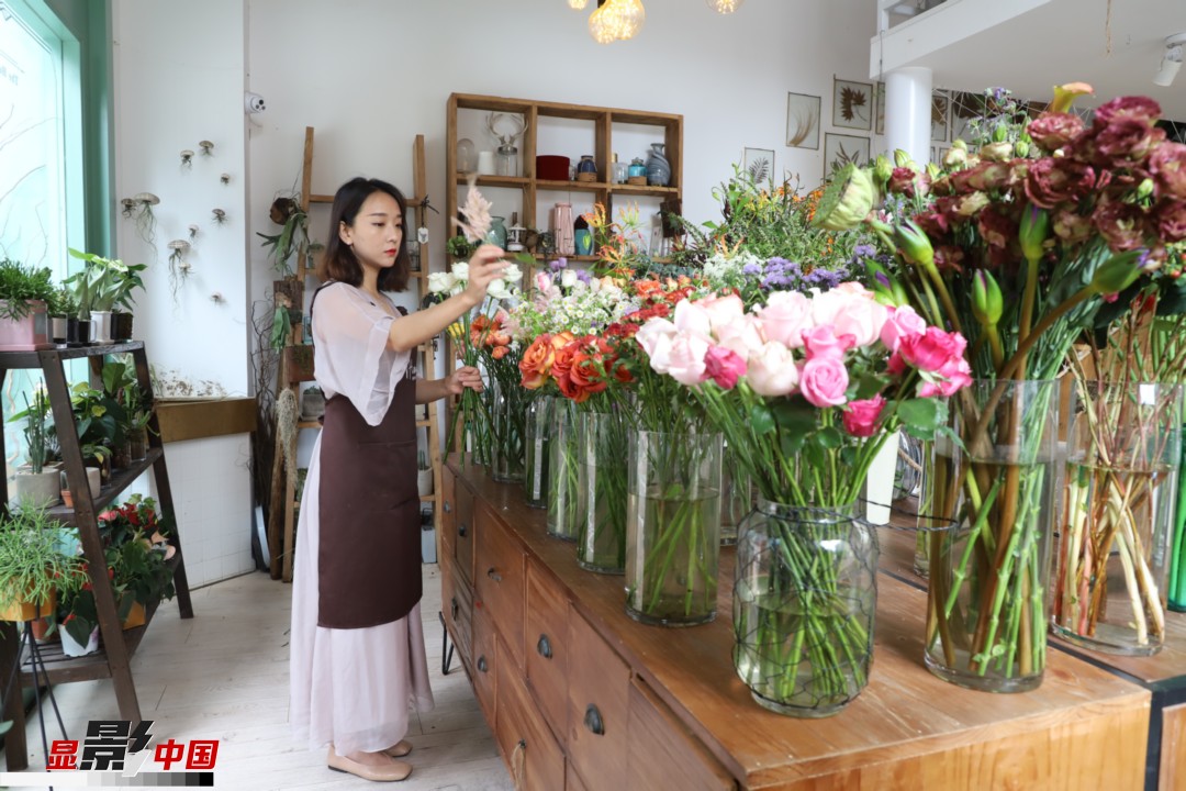 王黎媛是一名河南姑娘，在昆明念完大學(xué)后，就再也舍不下春城的藍(lán)天陽光、青山碧水，更舍不下這里的四時繁花，于是就干脆留了下來，成了一名媒體人。2017年的時候又毅然辭去工作，創(chuàng)業(yè)開起了花店，成了都市里的一名“花房姑娘”。圖為王黎媛在自己的花店中整理鮮花。新華網(wǎng) 周亞平/攝 念新洪/文